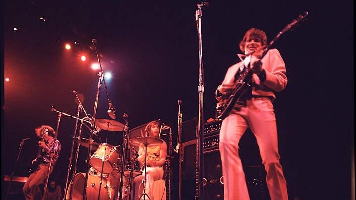 Creedence Clearwater Revival performing in the early 1970s, bathed in red stage light